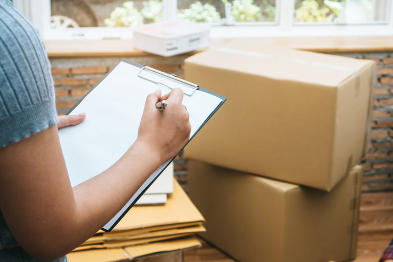 Happy woman checking stuff in cardboard box before sent to trans